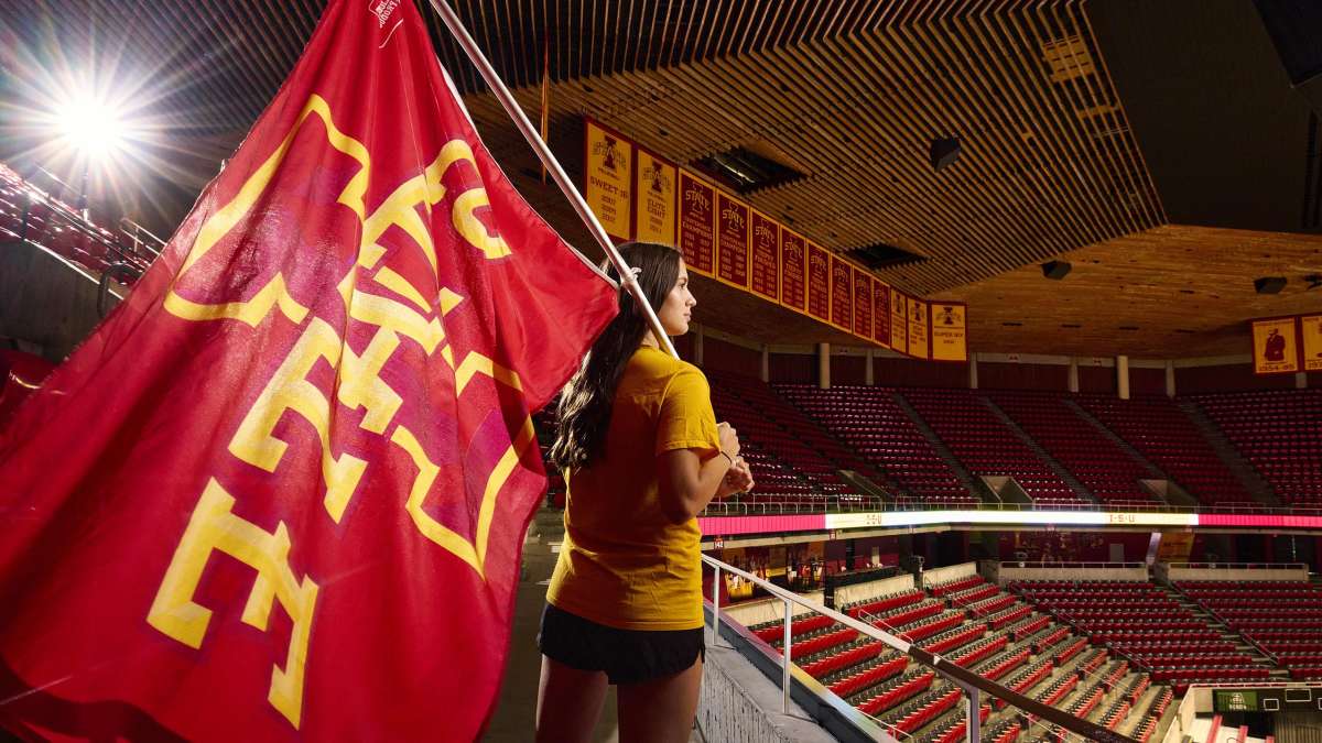 Erin Lowe holds an I-State athletics flag in Hilton Coliseum.