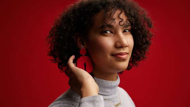 Head and shoulders shot of a young woman posing with a red background.