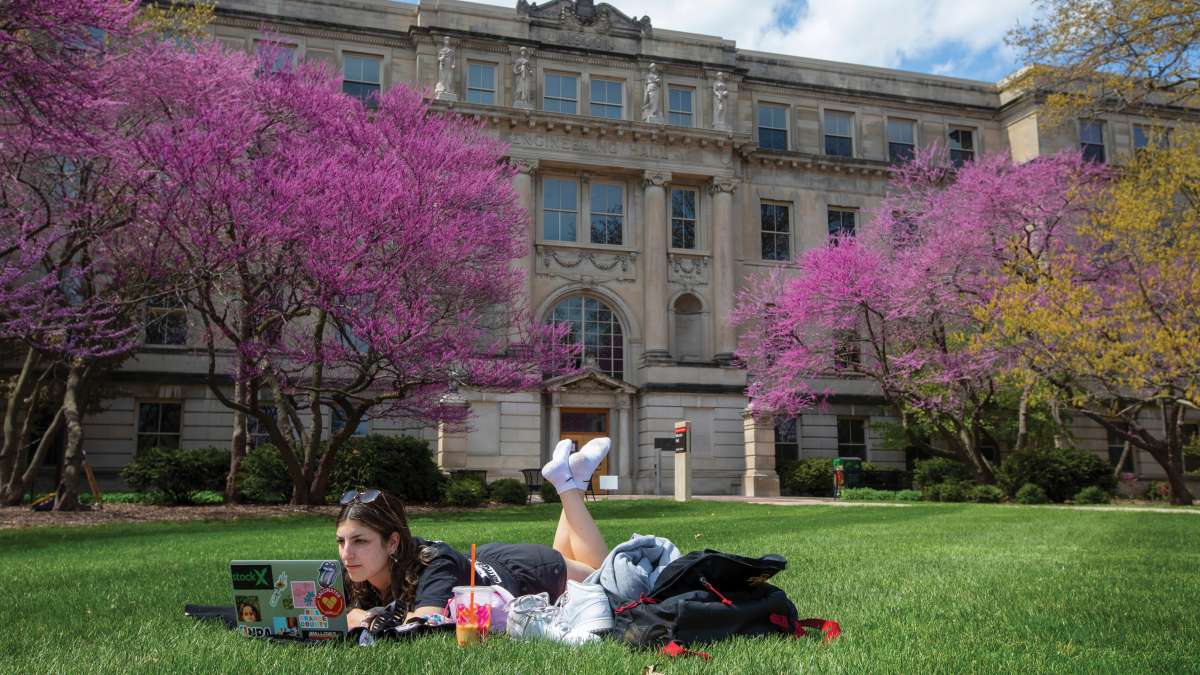 Student studies on lawn at Iowa State campus
